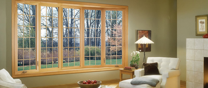 Living room with a wide wood-tone bow window looking onto trees
